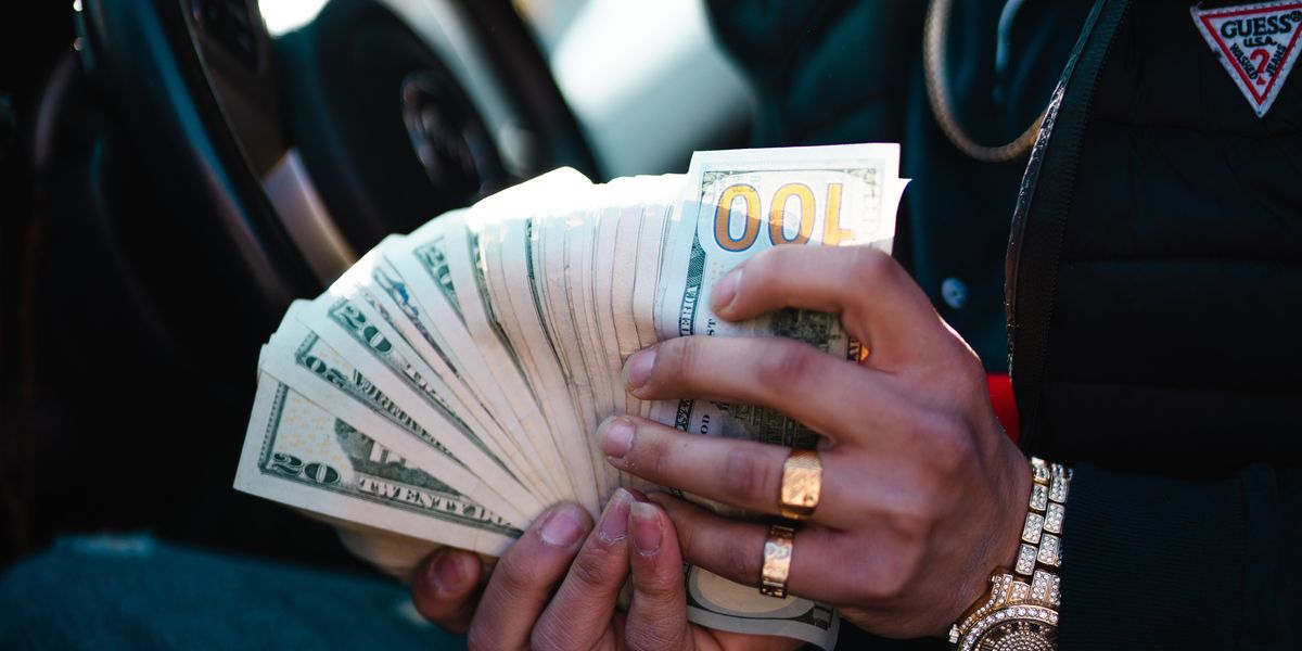man in car holding a lot of American money