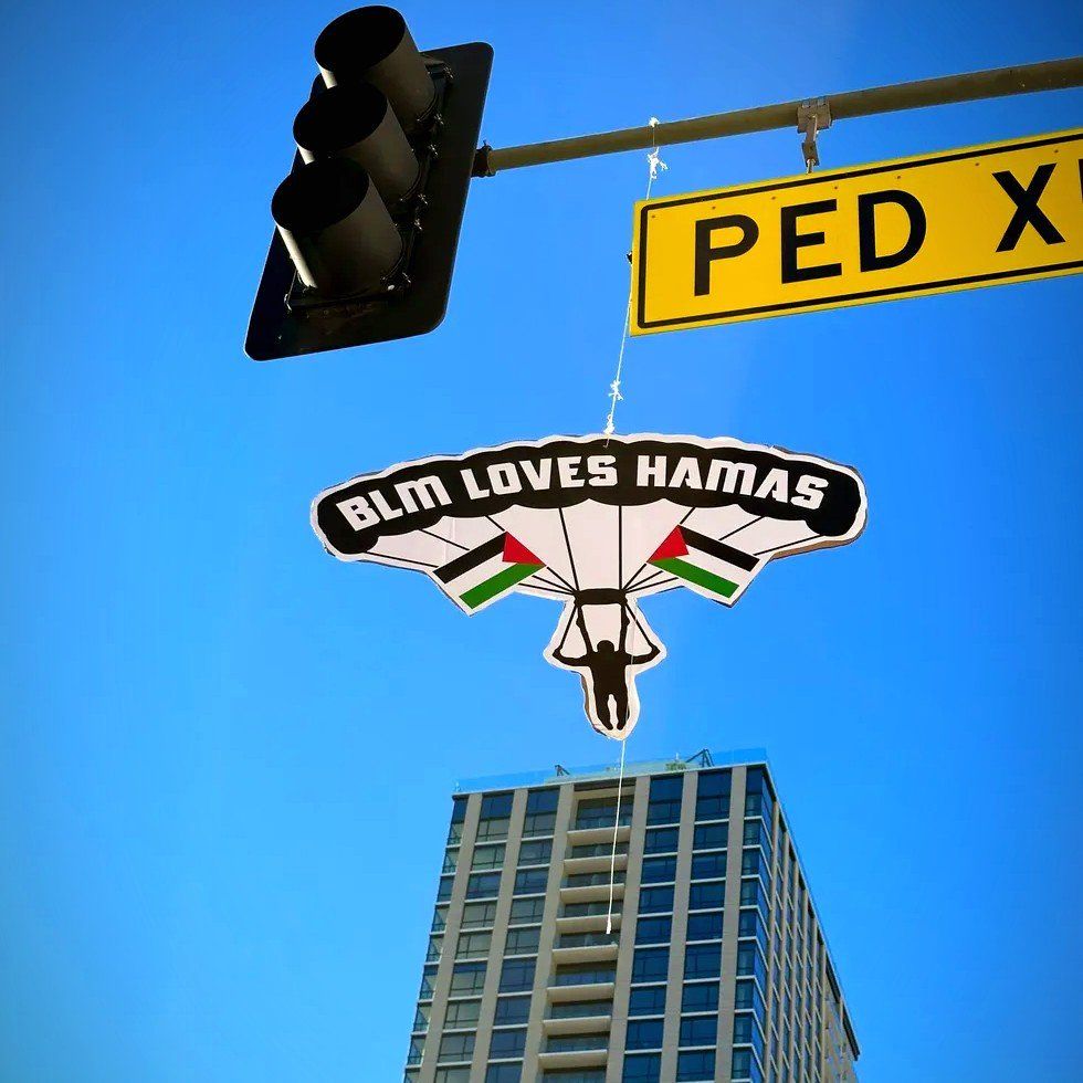 Sabo hangs his "BLM Loves Hamas Paraglider" pieces in Downtown LA.