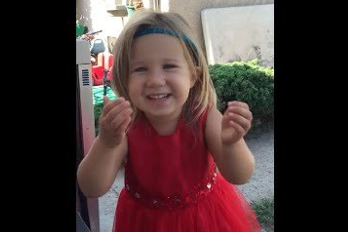 little girl in a red dress gesturing with her hands