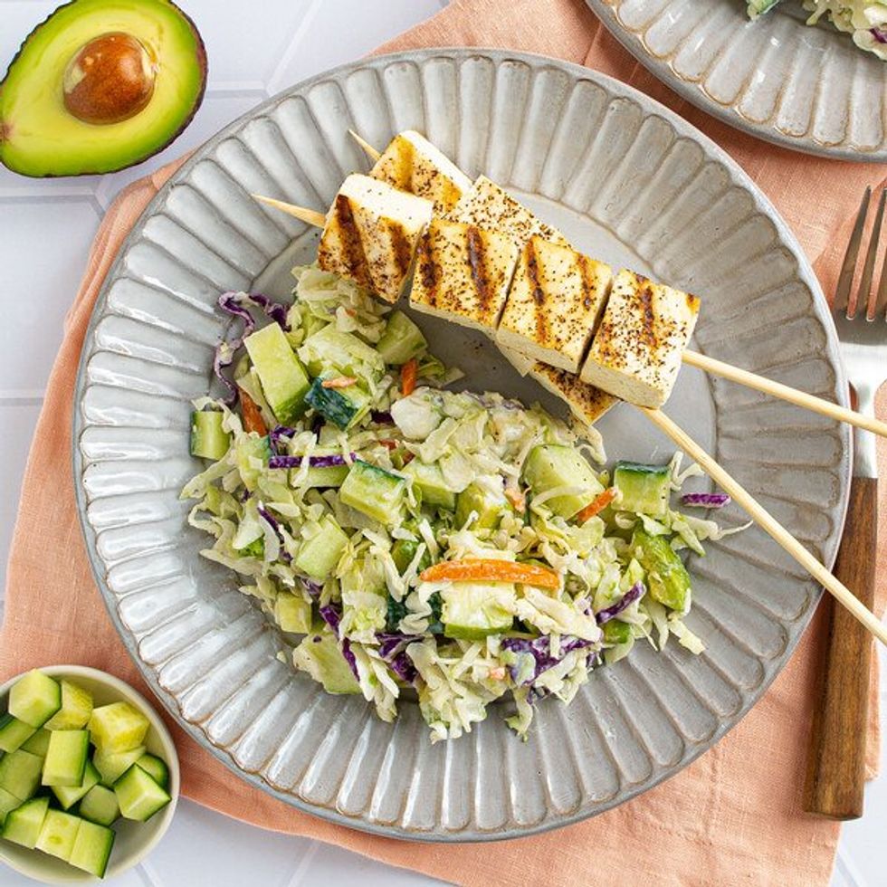tofu on skewers on a plate with coleslaw