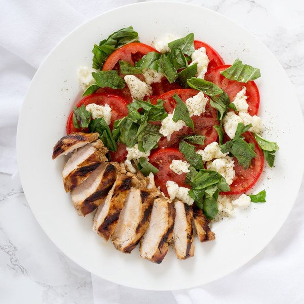 plate with slices of grilled chicken and a caprese salad
