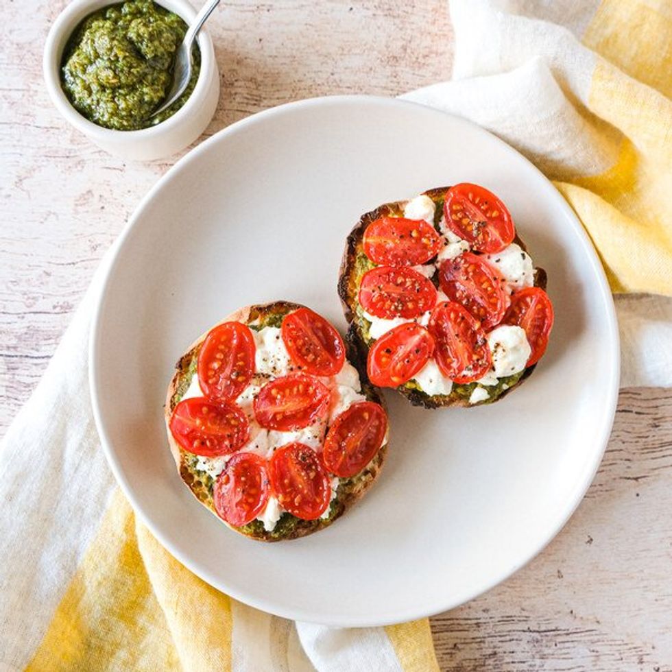 plate with open English muffin with goat cheese and sliced baby tomatoes on top