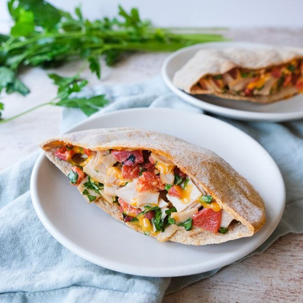 pita pocket on a plate filled with veggies, meat and cheese