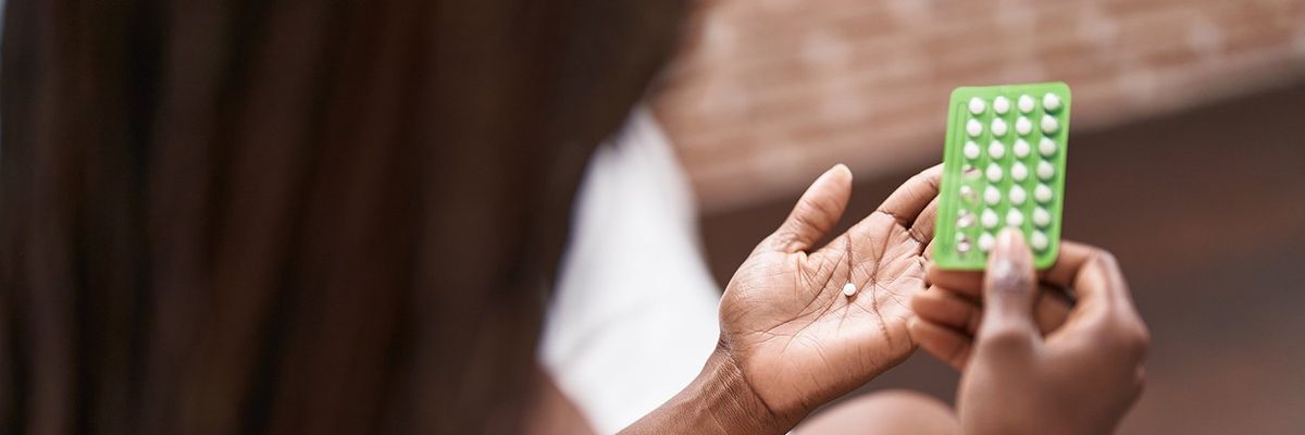 a woman hold a packet of birth control pills and a pill in her hand