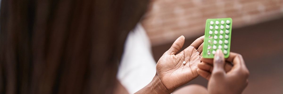 a woman hold a packet of birth control pills and a pill in her hand 