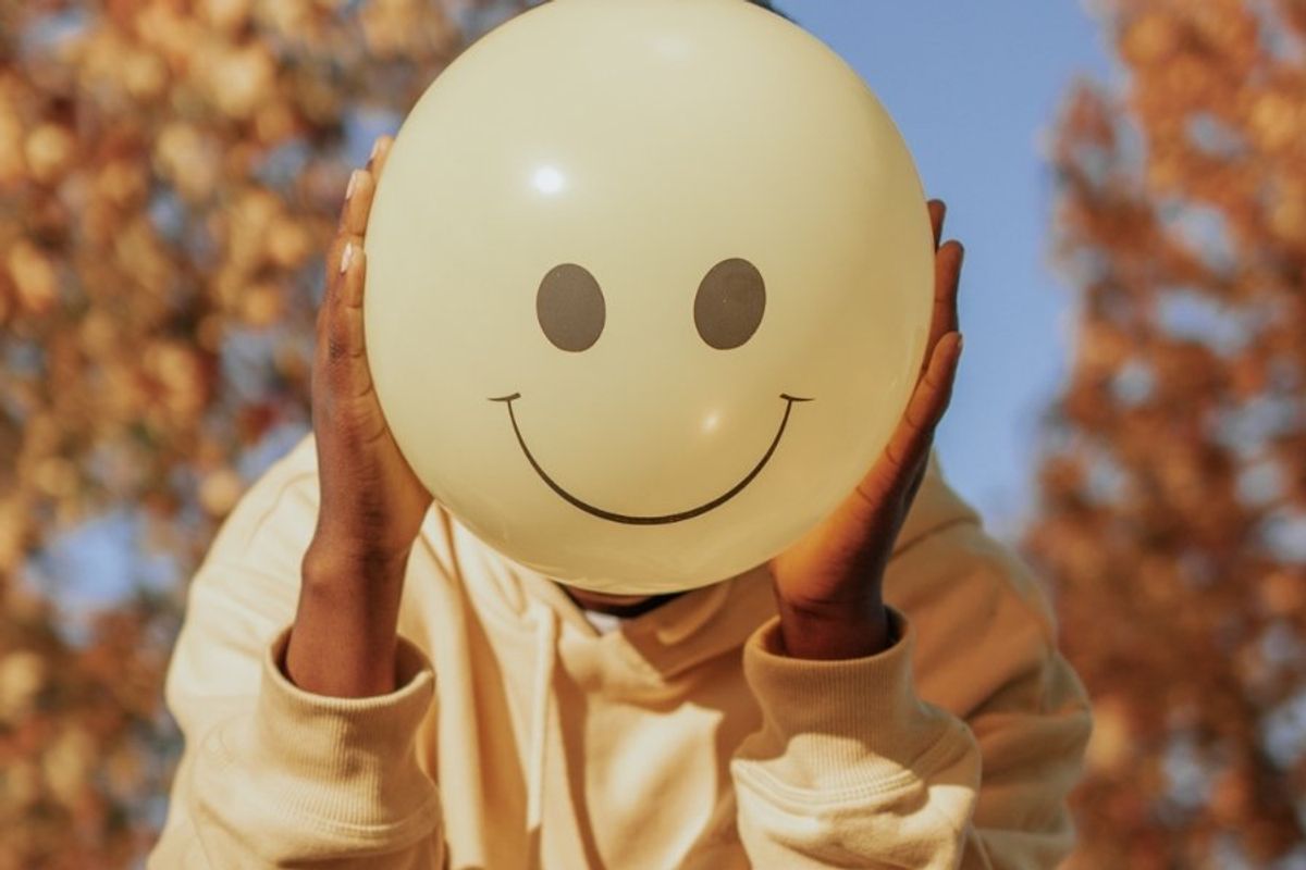 person holding a smiling balloon in front of their face