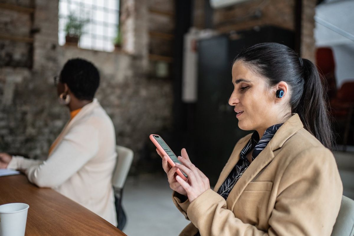 a woman wearing wireless earbuds on her smartphone