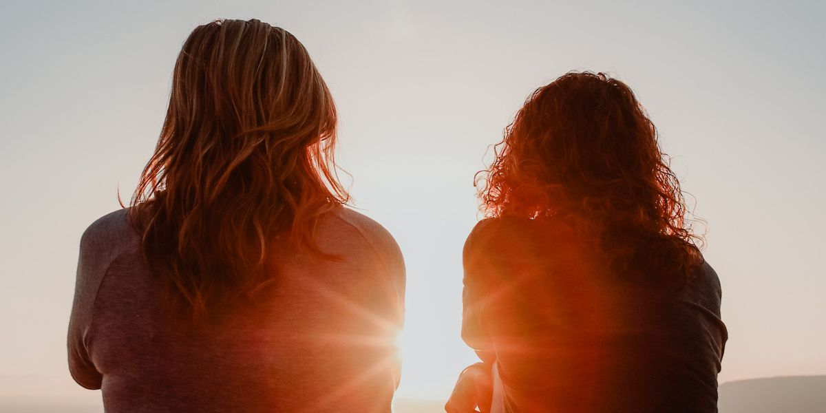 Two women looking on over a sunset