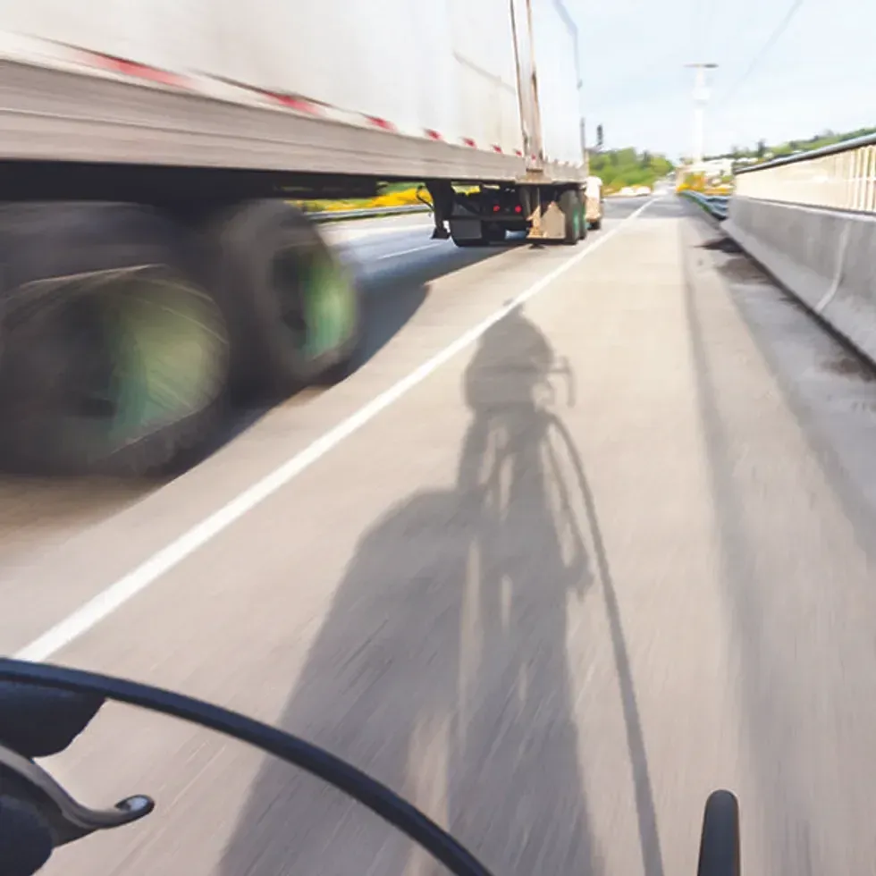 Truck driving next to a bicyclist.