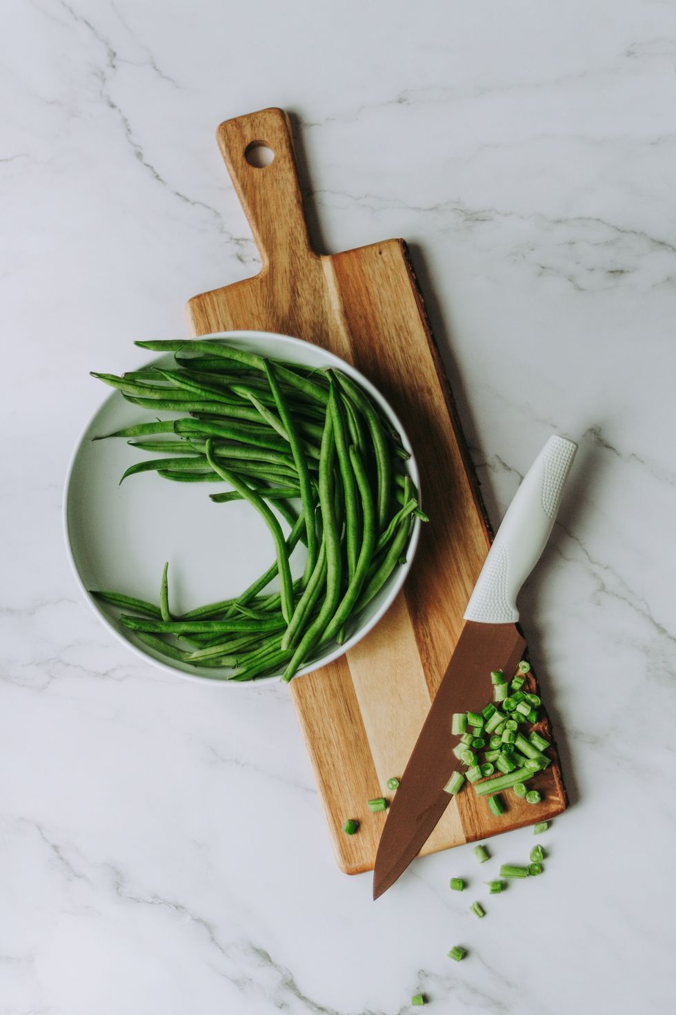 green beans on brown wooden chopping board with chef's knife