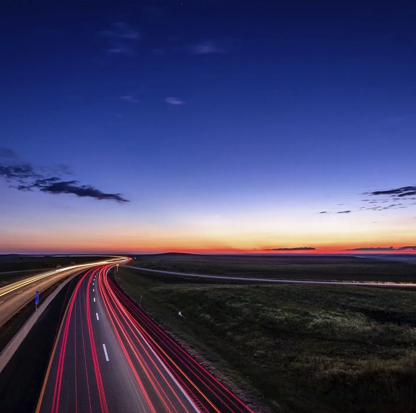 Red brake lights shine brightly on a road at night