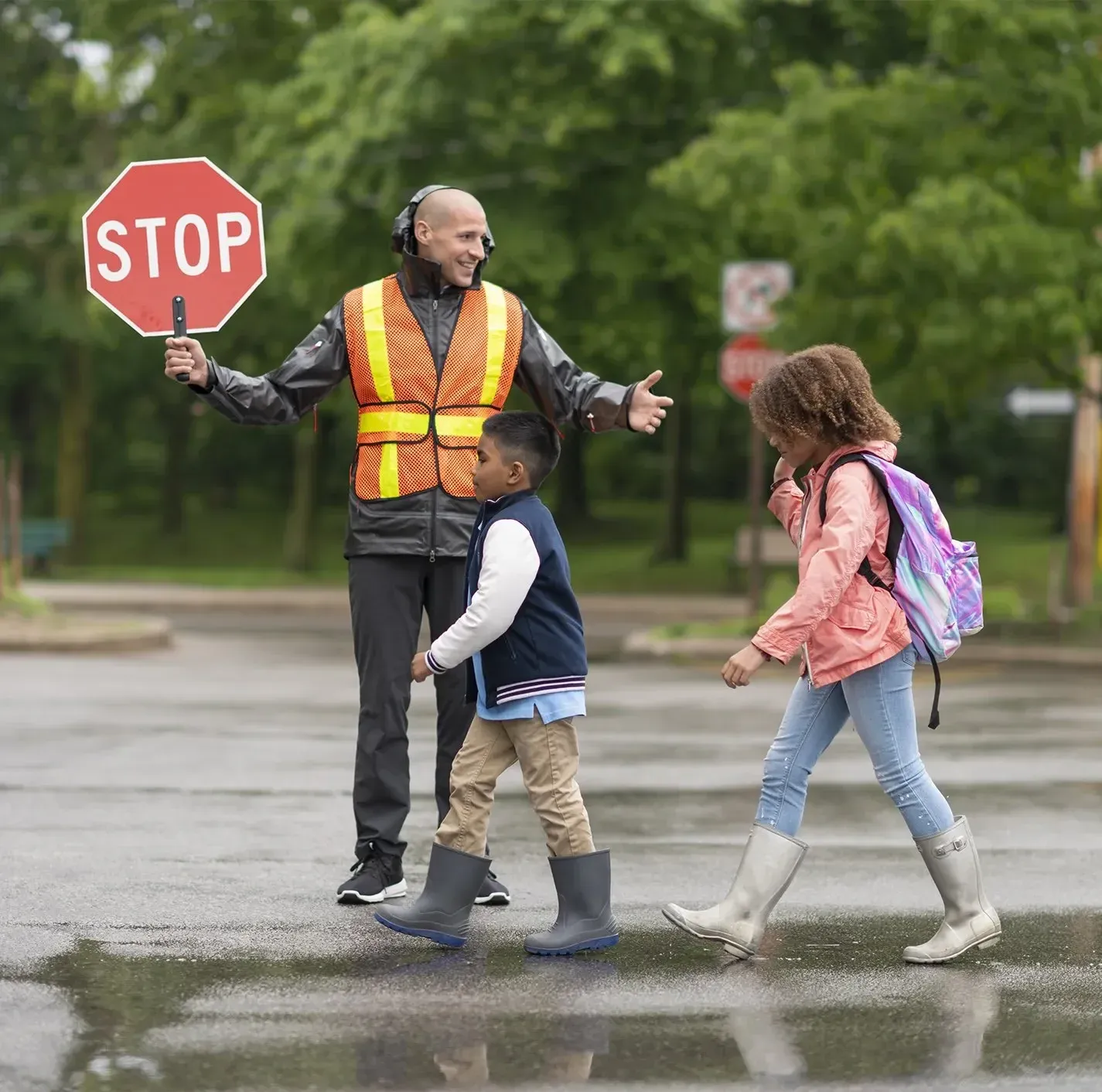 A crossing guard stops traffic as children cross the street
