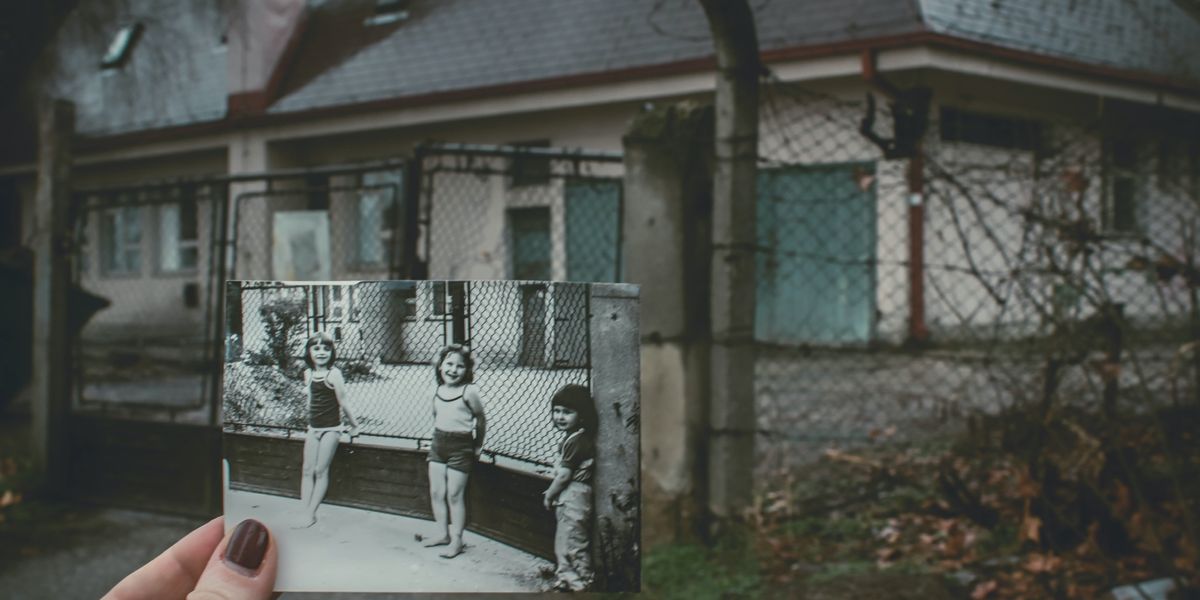person holding photo of three girls near chainlink fence