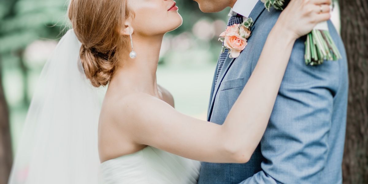 groom in gray suit kissing bride in white dress