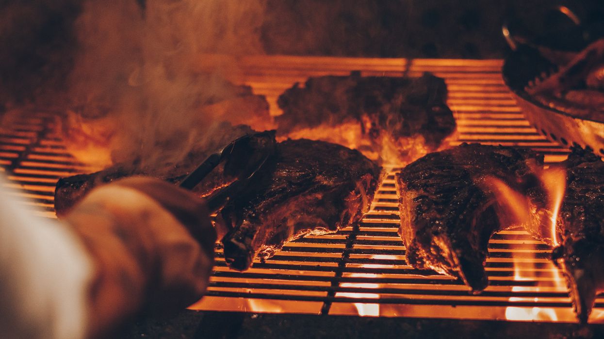 A man uses the fire and brimstone from the apocalypse to grill his steak dinner.