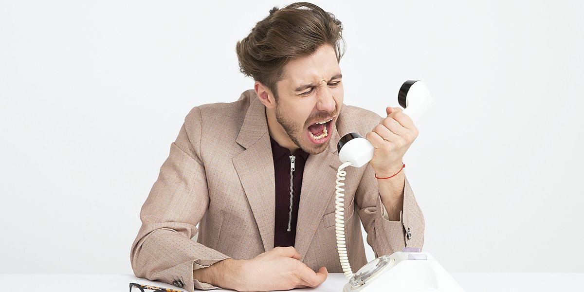 A well dressed man screams into a phone