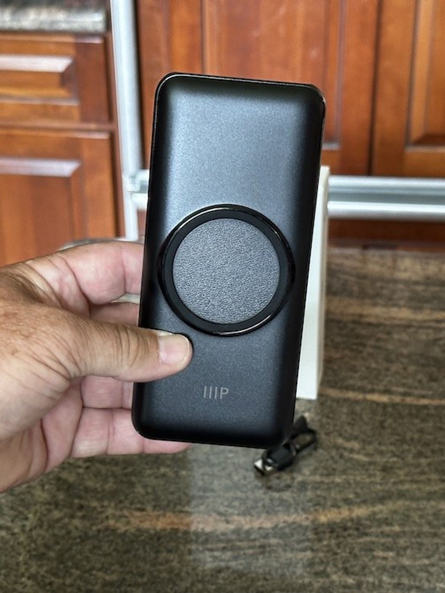 a photo of a hand holding Monoprice 20,000 mAh Power Bank with Wireless Charging