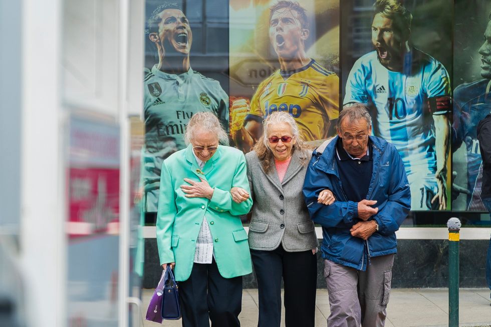 three older people walking arm in arm