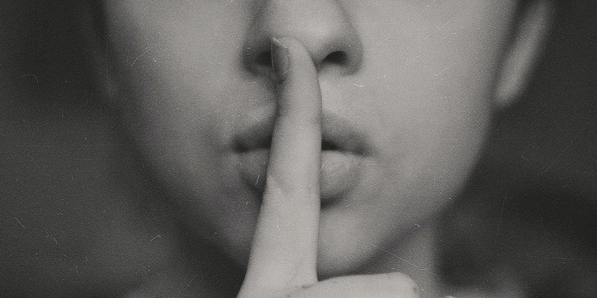 Woman making a "shh" gesture with one finger held up to her lips