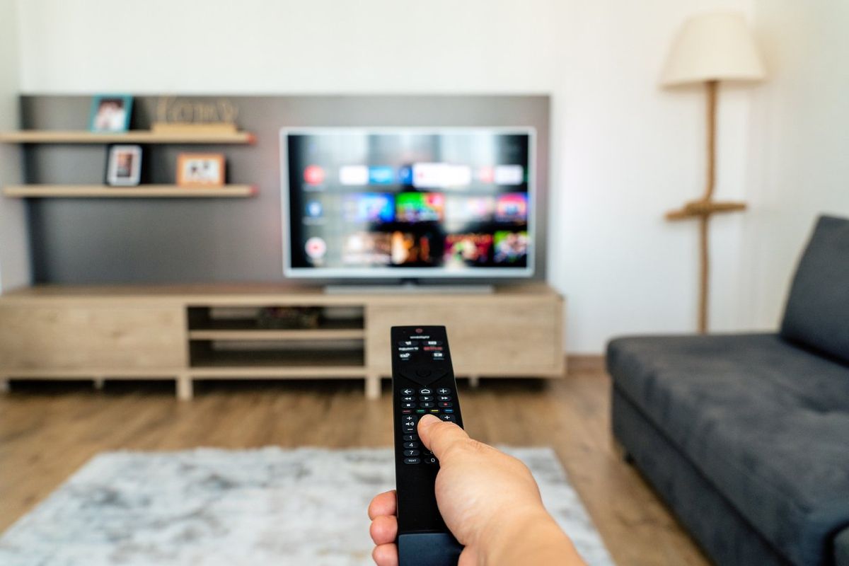 a photo of a person using a remote control on their smart tv