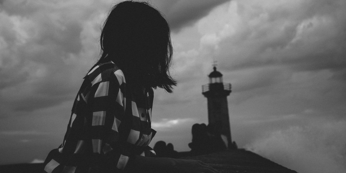 Black and white picture of a girl looking at a lighthouse