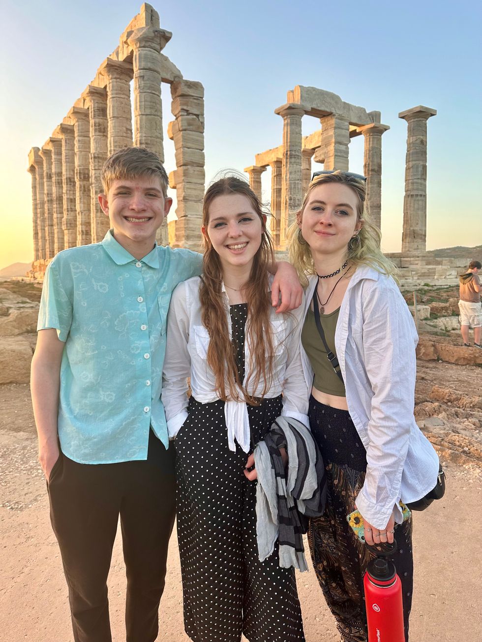 three young people in front of the temple of poseidon