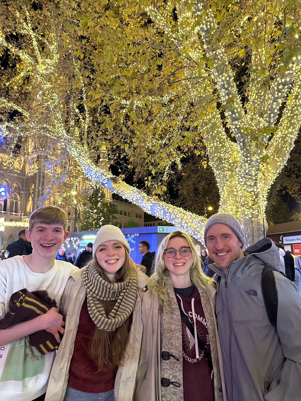Four people standing in front of a lit up tree