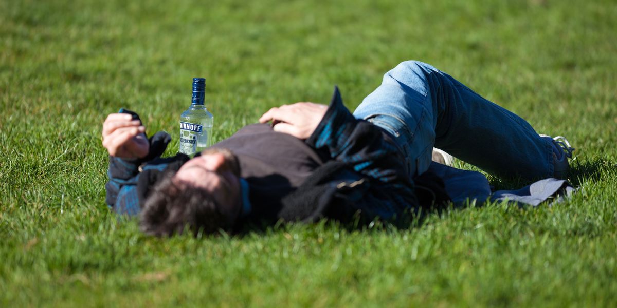 a man laying in the grass with a bottle of beer