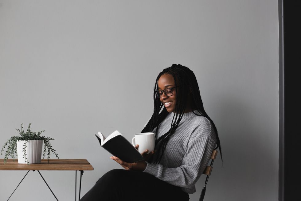 black-woman-in-white-and-black-stripe-long-sleeve-shirt-sitting-on-chair-reading-her-book