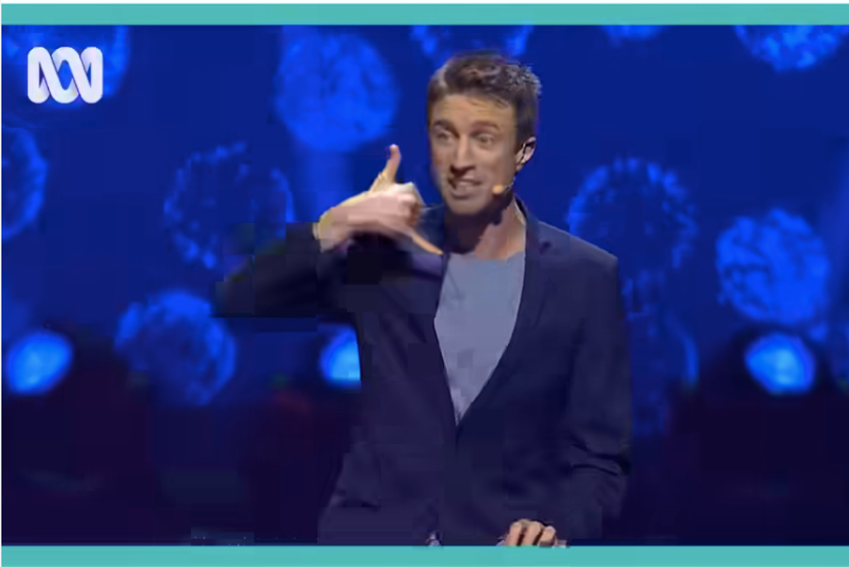 man on stage at the piano making a phone gesture with his hand