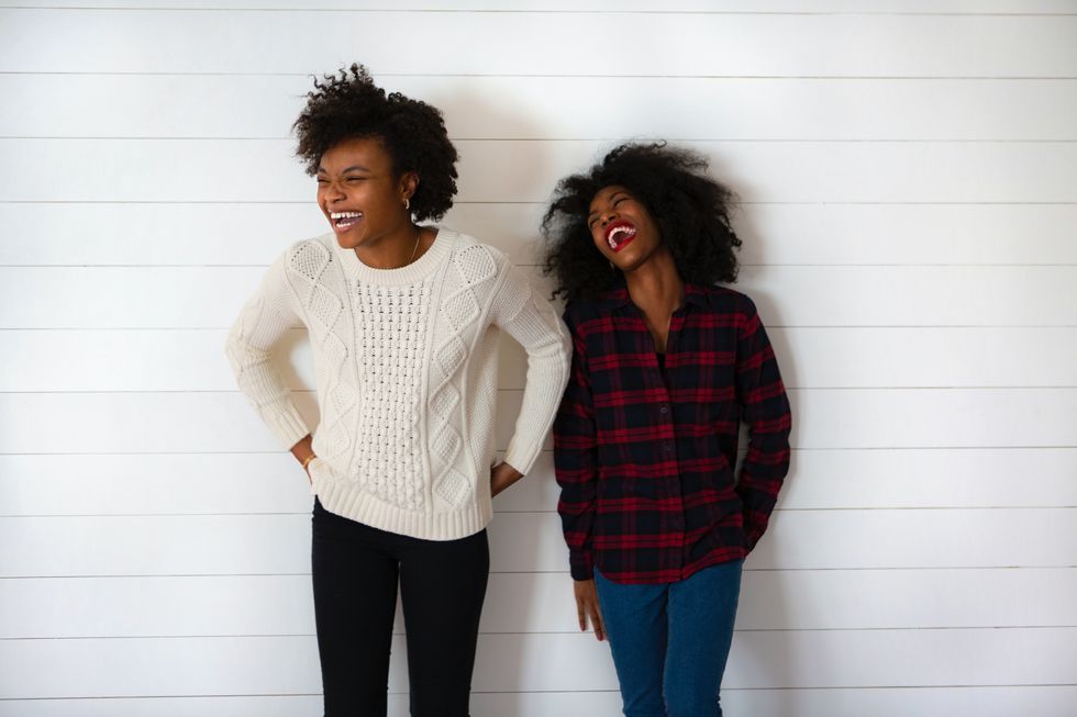 two-Black-women-laughing-wearing-holiday-sweaters