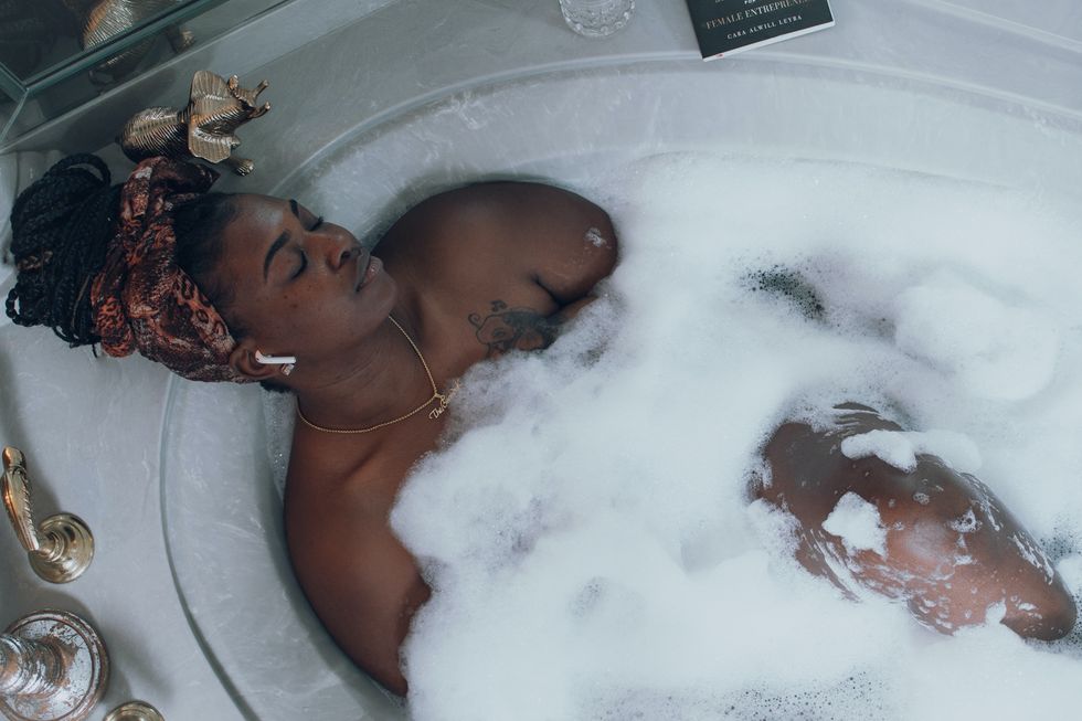 black-woman-braids-in-a-bun-relaxing-in-a-bubble-bath-listening-to-Airpods