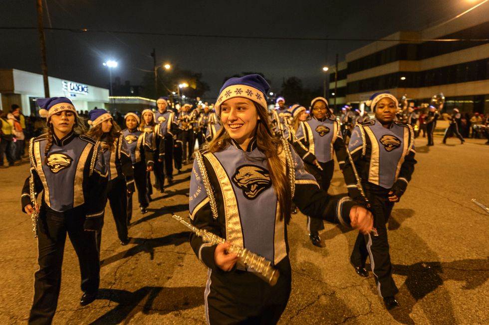 A high school marching band in matching blue uniforms and Santa hats marches in a Christmas parade.