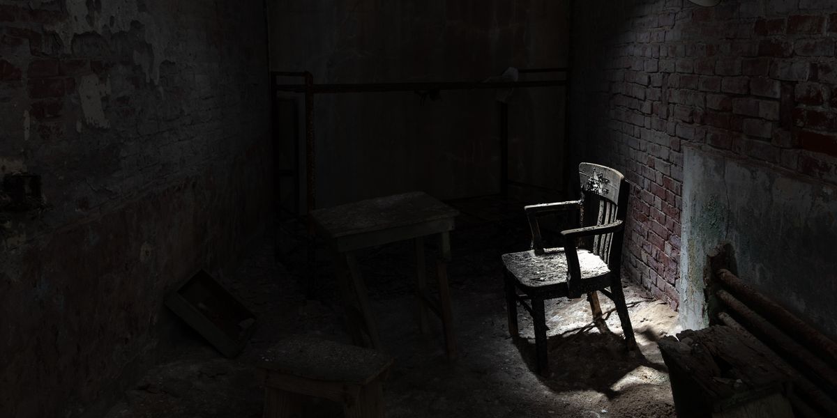 A chair lit by natural light in a dark room.