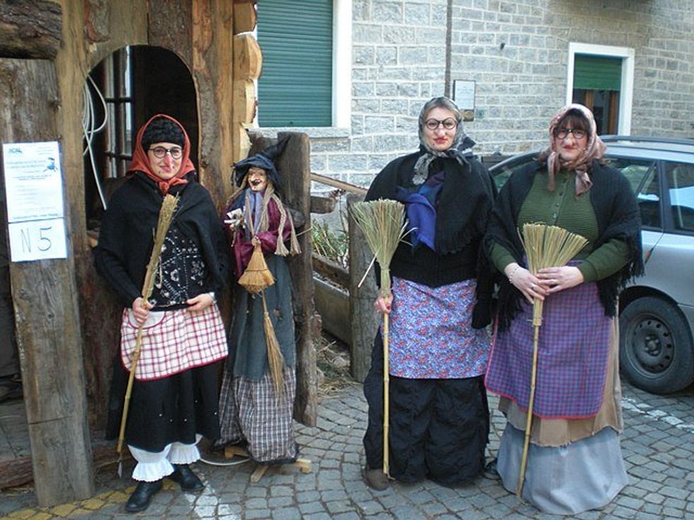 women in la befana costumes holding broomsticks