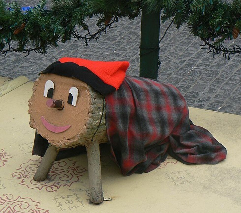 log with legs, a smiley face, a hat and a blenket