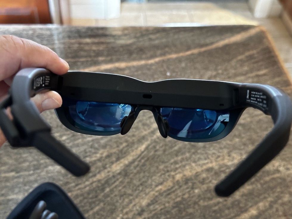 a photo of a person holding up Lenovo Legion AR glasses