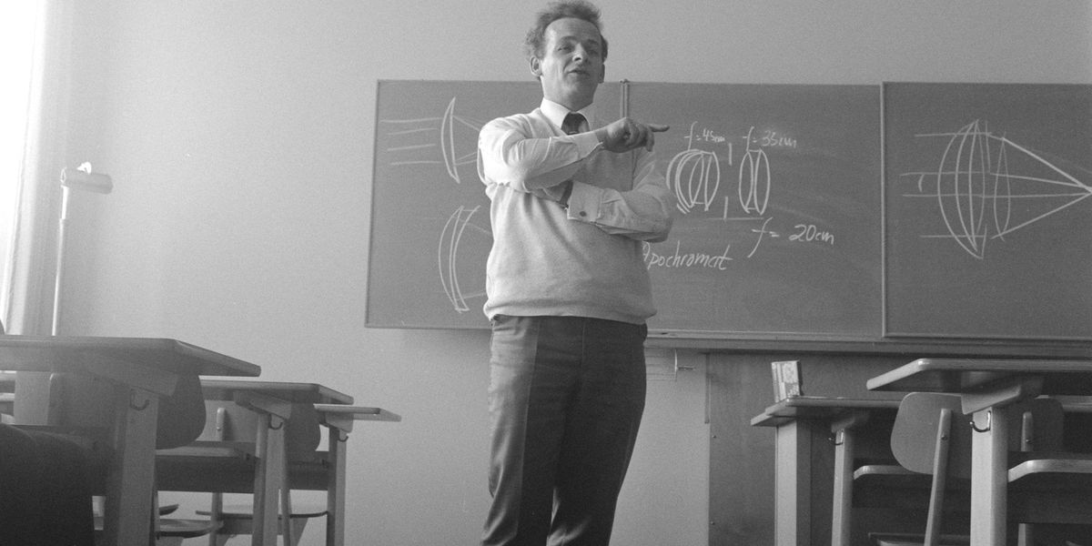 Black and white photo of a teacher pointing his finger toward an unseen student