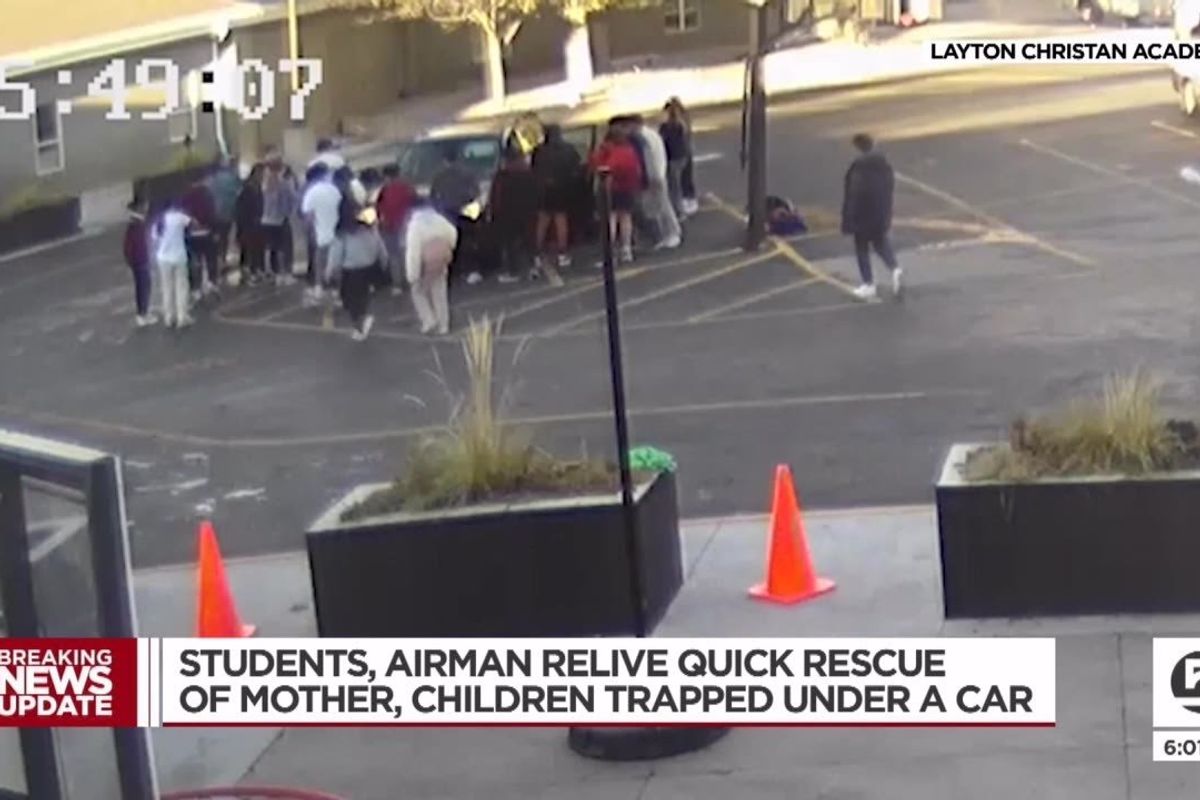 group of teens lifting car in parking lot