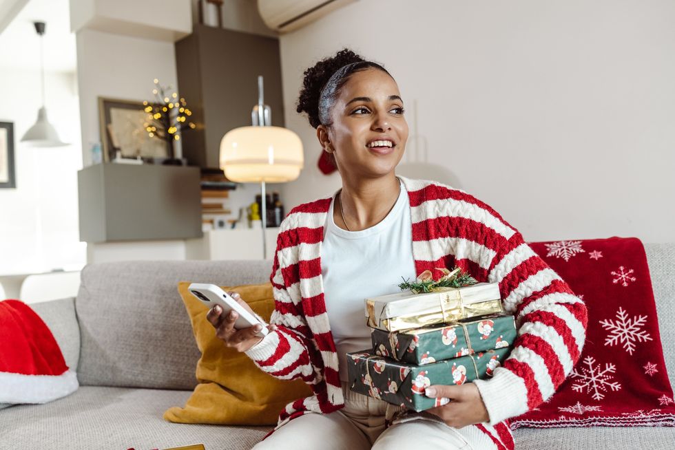 woman-sitting-on-couch-with-Christmas-decorations-and-wrapped-presents-in-her-hand