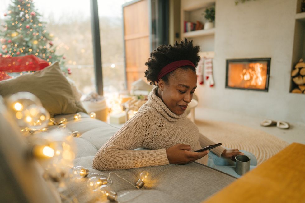 woman-scrolling-on-her-phone-while-decorating-her-home-for-Christmas