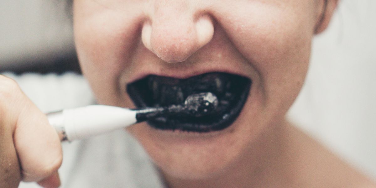 Person brushing with charcoal toothpaste