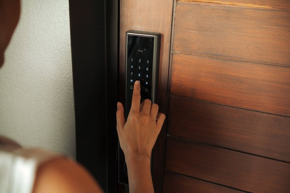 a woman using the keypad on her smart lock to enter her home