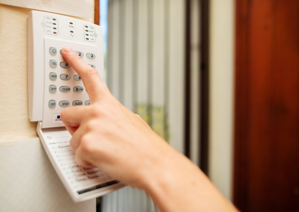 a person punching in their code on their home security keypad