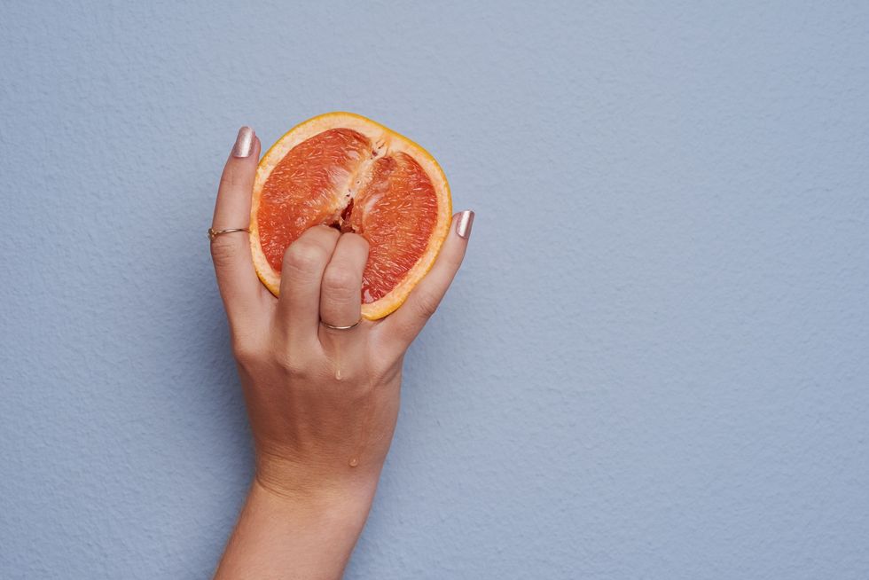 woman's-hand-holding-half-of-a-citrus-fruit