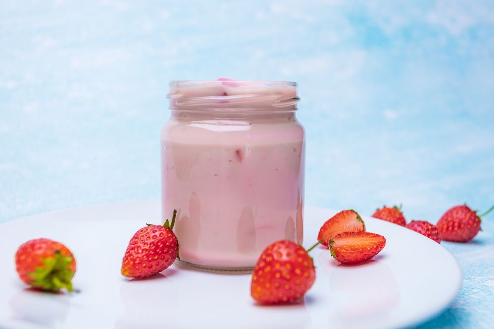 open-jar-of-pink-kefir-milk-near-cut-strawberries
