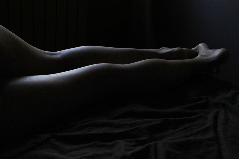 shadowy-image-of-close-up-of-legs-against-black-sheets
