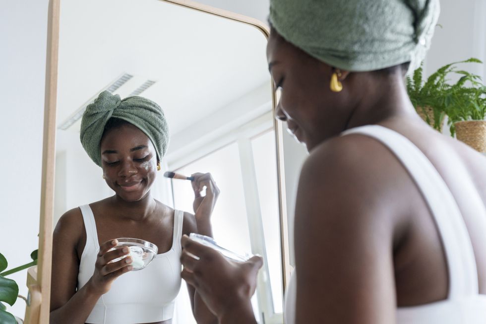 Smiling-Black-woman-applying-face-mask-in-a-self-care-moment