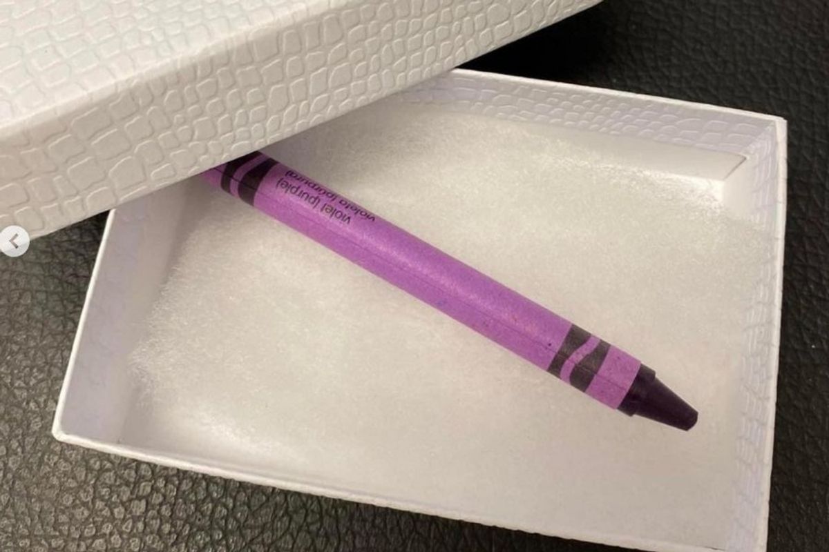 a purple crayon in a white gift box