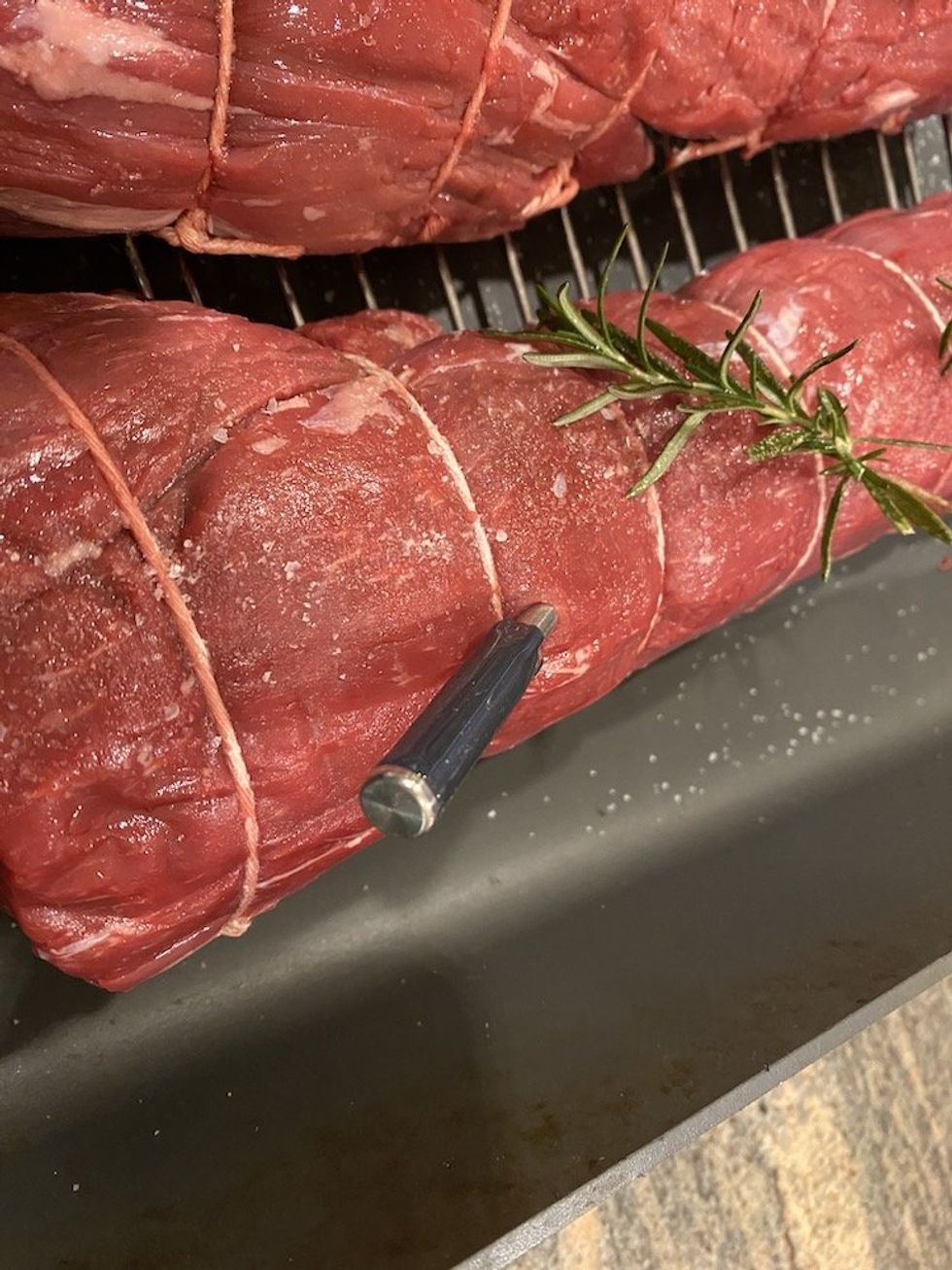 a photo of a smart meat thermometer inserted in a roast beef which is in a pan.
